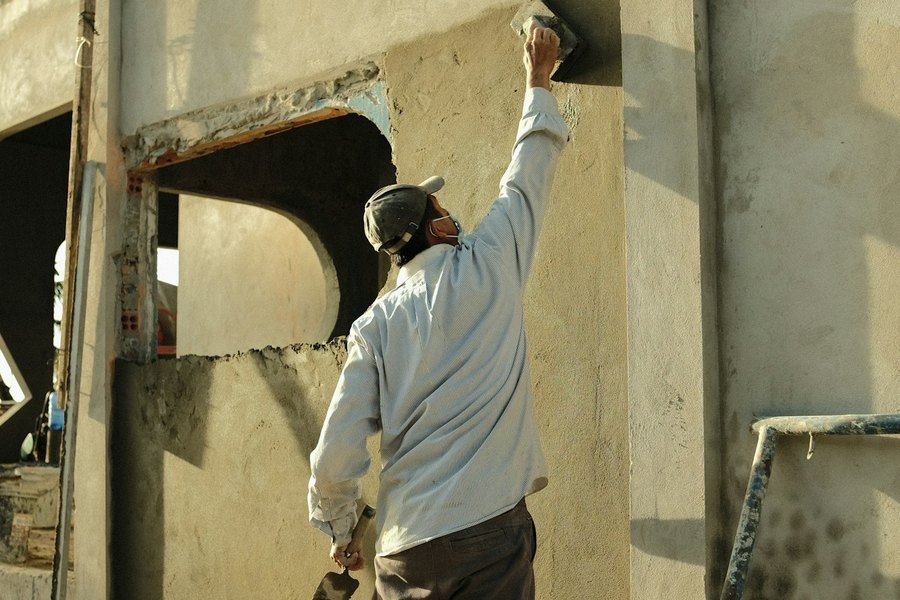 Plasterer floating a fresh render coat onto an external wall